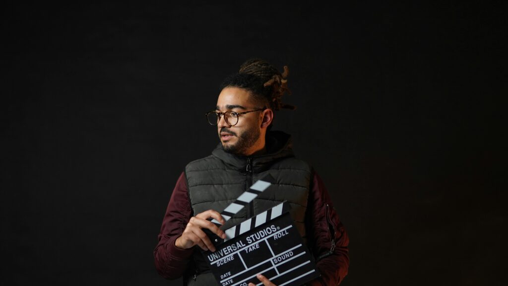 A filmmaker holding a clapperboard against a black background, emphasizing cinematic creativity.