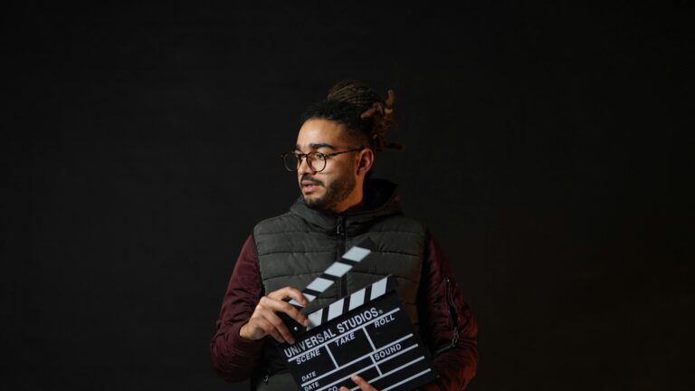 A filmmaker holding a clapperboard against a black background, emphasizing cinematic creativity.