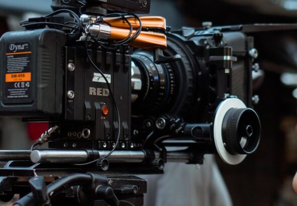 Close-up of professional video camera and crew on an outdoor film set.